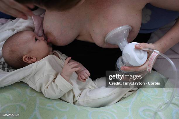 Two month old baby girl baby breast feeding as her mother uses a milk pump to express milk into a container on her other breast. Photo Tim Clayton