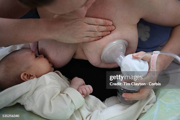 Two month old baby girl baby breast feeding as her mother uses a milk pump to express milk into a container on her other breast. Photo Tim Clayton