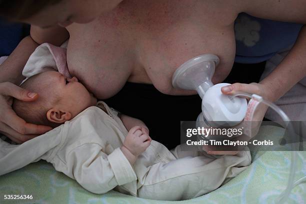 Two month old baby girl baby breast feeding as her mother uses a milk pump to express milk into a container on her other breast. Photo Tim Clayton