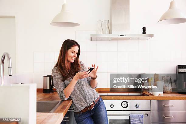 middle-aged woman texting on her smartphone - oven dial stock pictures, royalty-free photos & images