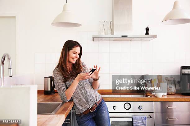 middle-aged woman texting on her smartphone - cooker dial stock pictures, royalty-free photos & images