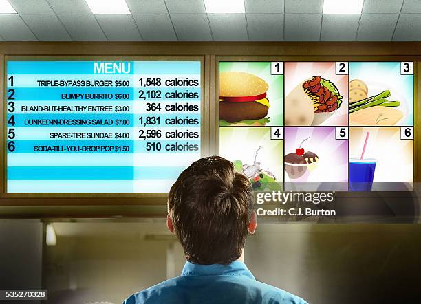 man reading fast food menu with calorie chart - fast food restaurant foto e immagini stock