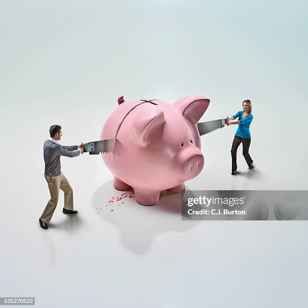 couple sawing piggy bank in half - couple saving piggy bank stock pictures, royalty-free photos & images