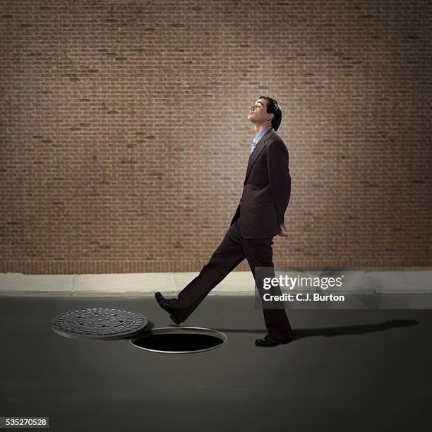 businessman walking over open manhole - ignorance foto e immagini stock