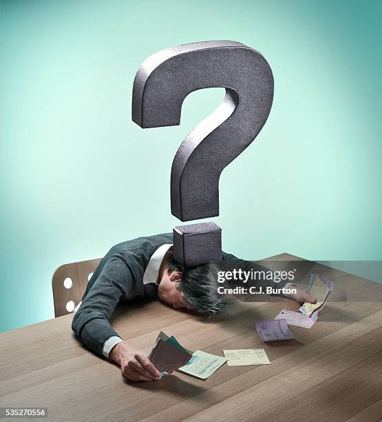 metal question mark over man holding bills - futility stock pictures, royalty-free photos & images