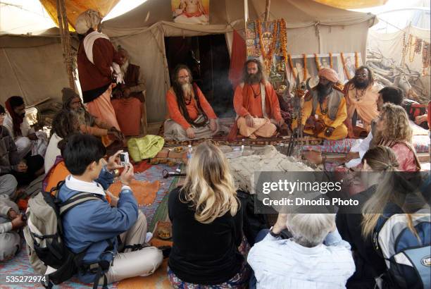 sadhus from the juna akadha sit with their disciples, most of them foreigners, at their camp during the ardh kumbh mela in allahabad, uttar pradesh, india. - allahabad ストックフォトと画像