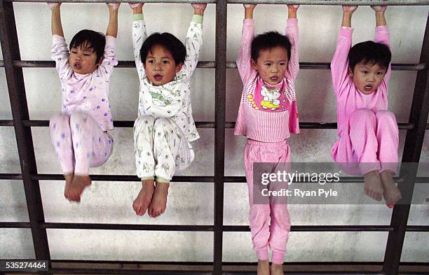 Group of girls do knee bends at the Li Xiaoshuang Gymnastics School in Xiantao, China. Li Xiaoshuang was a sucessful Chinese gymnast who was born in...