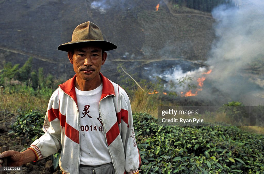 China - Yunnan - Xishuangbanna - A Farmer With the Burning Hillside in Background