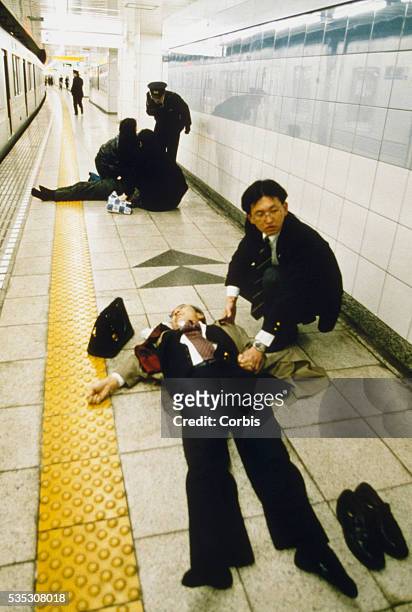 Transit worker sits beside the body of a man felled by the sarin gas attack on the Tokyo subway system. The attack, by the religious group Aum...