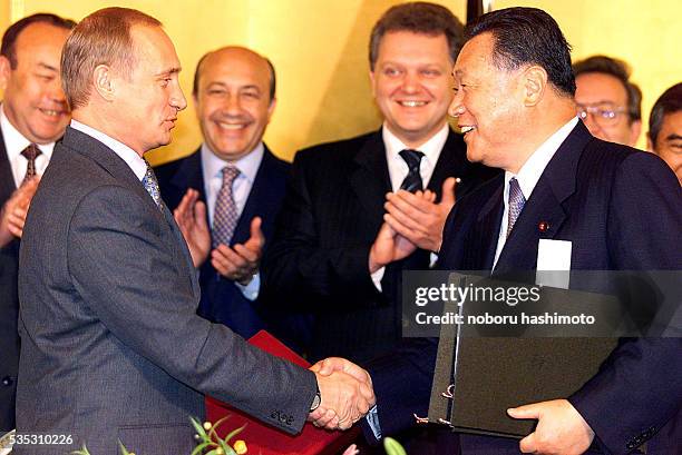 Russian President Vladimir Putin shakes hands with Japanese Prime Minister Yoshiro Mori as they exchange documents on their agreement during the...