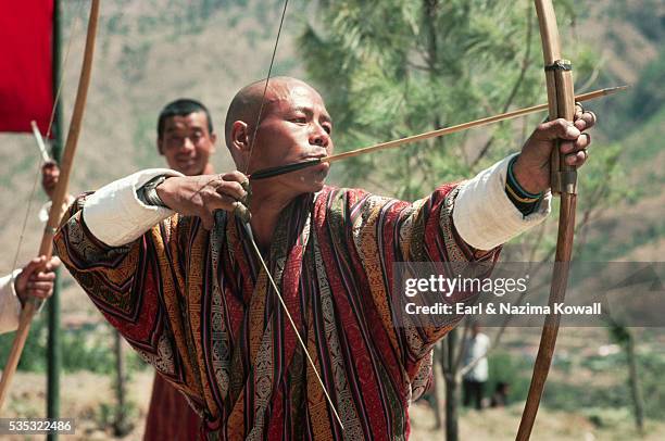 archer aiming arrow in thimphu contest - bhutan archery stock pictures, royalty-free photos & images