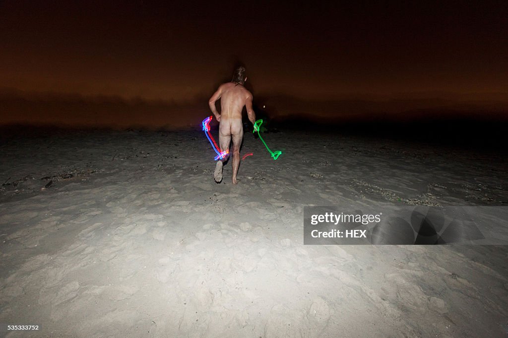 Young man streaking on a beach at night