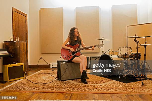 young woman playing an electric guitar - woman playing guitar stock pictures, royalty-free photos & images