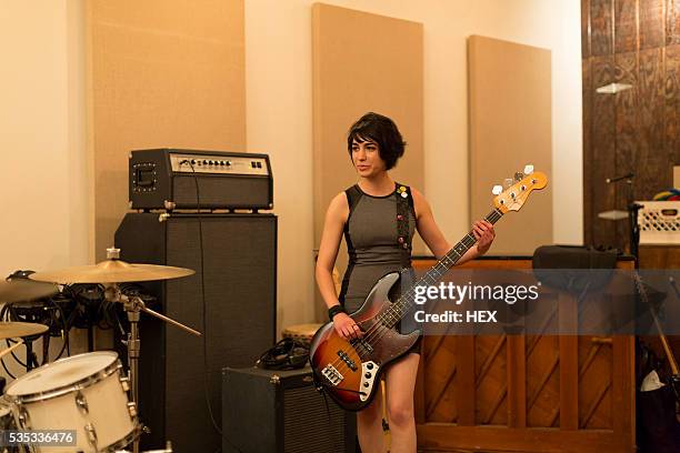 young woman playing a bass guitar - bass stockfoto's en -beelden