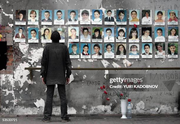 Beslan, RUSSIAN FEDERATION: A man looks at pictures of children killed last year in the school sports hall of Beslan, 30 August 2005. Russia marks 01...