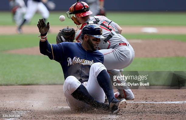 Jonathan Villar of the Milwaukee Brewers slides into home plate to score a run past Tucker Barnhart of the Cincinnati Reds in the third inning at...