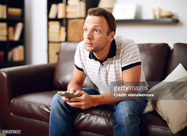 man in home interior watching tv - bad news on tv stock pictures, royalty-free photos & images