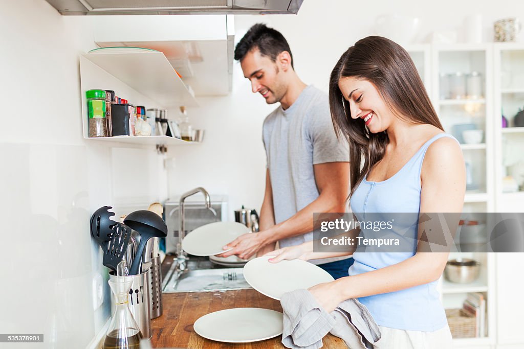 Couple at home washing dishes.