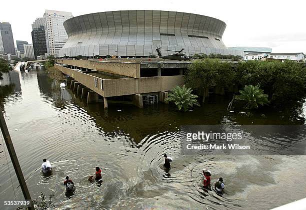People walk through high water in front of the Superdome August 30, 2005 in New Orleans, Louisiana. Thousands of people are left homeless after...