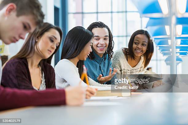 multiracial students studying in library - homework table stock pictures, royalty-free photos & images