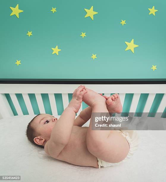 playing with his toes - baby cot stock pictures, royalty-free photos & images