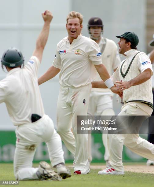 Australia's Shane Warne runs into congratulate Simon Katich after he caught out New Zealand Black Caps Nathan Astle on 69 runs off Warne's bowling...