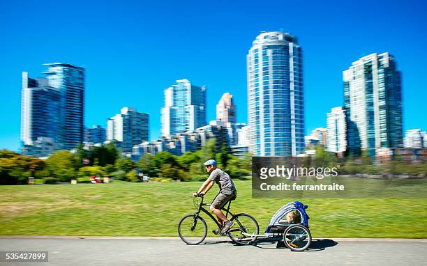 father carries son in bicycle trailer in vancouver canada - vancouver canada stockfoto's en -beelden