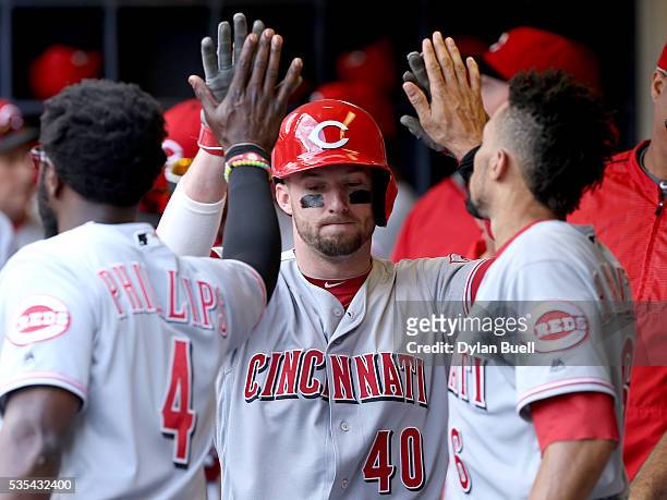 Tyler Holt of the Cincinnati Reds is congratulated by teammates after scoring a run in the ninth inning against the Milwaukee Brewers at Miller Park...