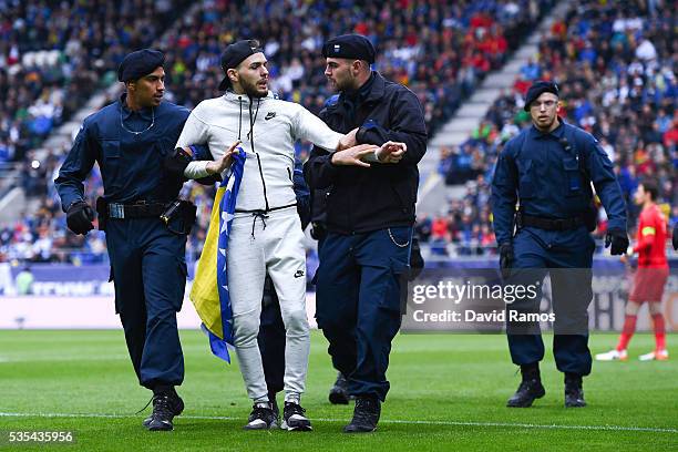 Security staff hold a Bosnia fan after he jumped onto the pitch during an international friendly match between Spain and Bosnia at the AFG Arena on...