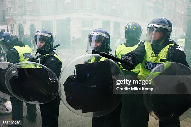 Riot police surrounded by yellow smoke from a smoke bomb stand their ground after a clash on a street in Mayfair. Anti capitalists / anarchists go on...