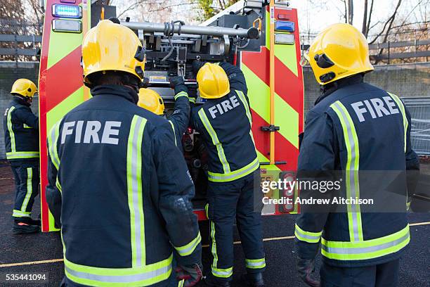 London Fire Brigade, station training session. Fire fighters get the ladders off the fire engine.