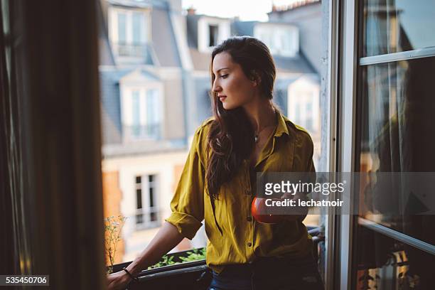 young woman relaxing on the balcony of her parisian apartment - sassy paris stock pictures, royalty-free photos & images