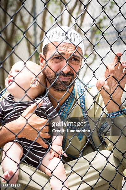 muslim refugee holding his baby - refugee camp stock pictures, royalty-free photos & images