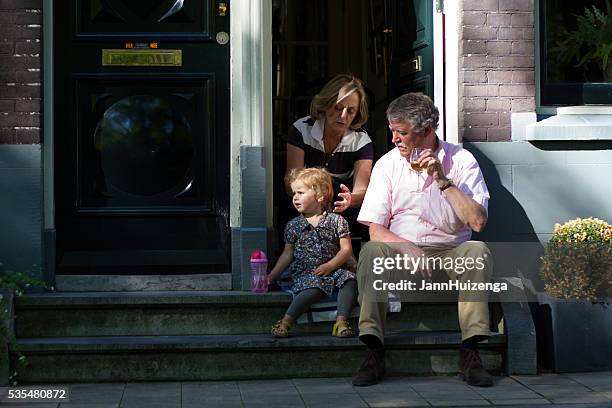 amsterdam, holland: family on front stoop with drinks - dutch family stockfoto's en -beelden