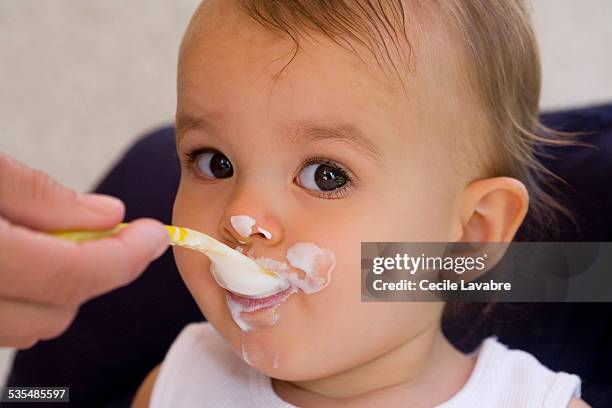 baby girl spoon fed with yogurt - baby eating yogurt stockfoto's en -beelden