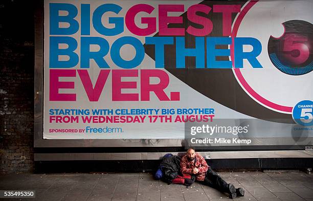 Homeless man lying underneath a billboard advertising poster for the latest series of Big Brother. The new series of the celebrity version of the hit...