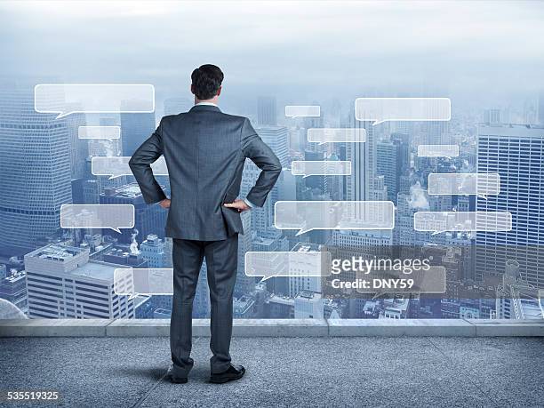 businessman staring at a large city full of text bubbles - hand on hip stock pictures, royalty-free photos & images