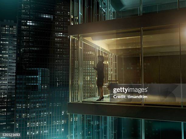 woman in an office by night - business woman looking through window stock pictures, royalty-free photos & images