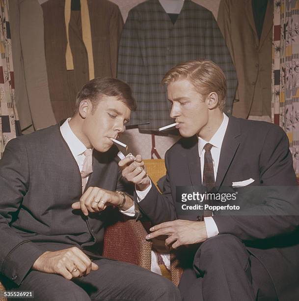 English singers Mike Sarne and Marty Wilde smoke cigarettes together backstage in their dressing room before a concert performance in England in 1962.