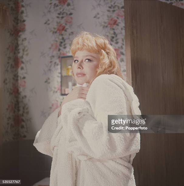 English actress Janet Munro pictured wearing a white towelling robe on a film set in 1962.