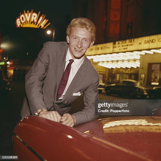 Manchester United and Scotland footballer, Denis Law posed outside the Odeon Cinema in Oxford Street, Manchester in 1962. A large Bovril neon sign is...