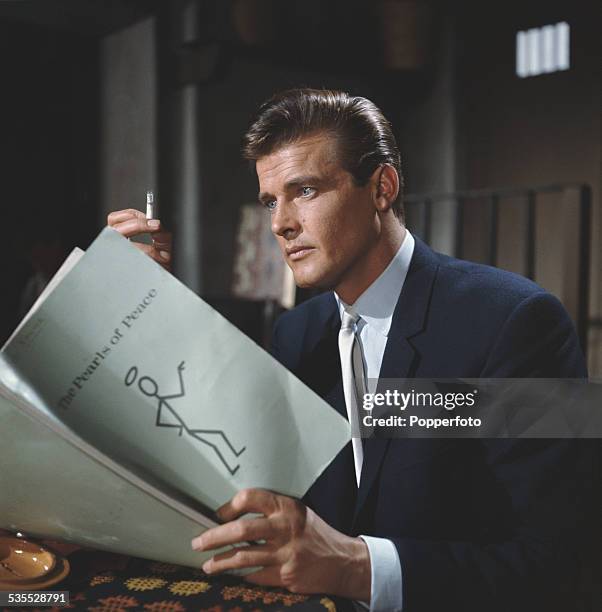 English actor Roger Moore, who plays the character of Simon Templar in the television series 'The Saint', pictured holding a script for The Pearls Of...