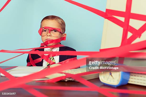 young boy in business suit covered in red tape - administrative professional stock pictures, royalty-free photos & images