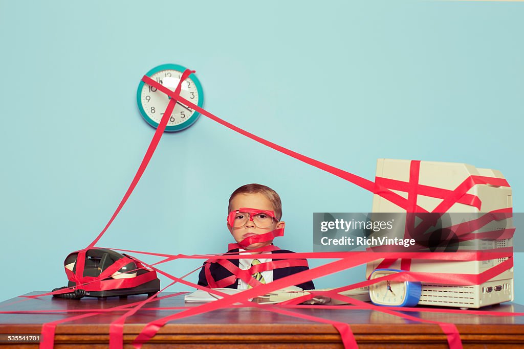 Young Boy in Business Office is Covered in Red Tape