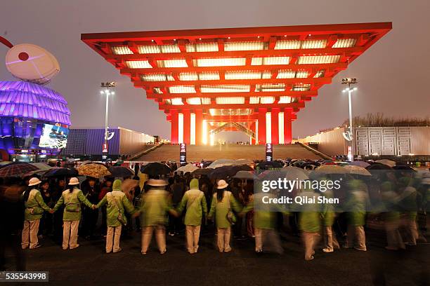 Volunteers form a human chain as visitors wait in line to enter the China Pavilion during the first day of the trail run for the 2010 World Expo in...