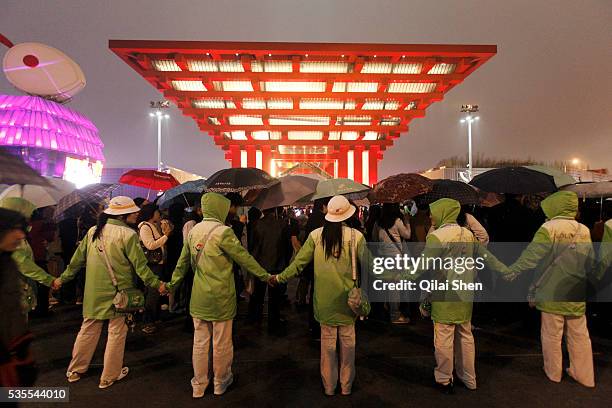 Volunteers form a human chain as visitors wait in line to enter the China Pavilion during the first day of the trail run for the 2010 World Expo in...