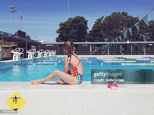child sitting on the edge of swimming pool - buitenbad stockfoto's en -beelden