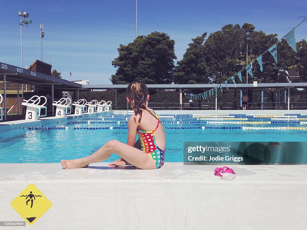 Child sitting on the edge of swimming pool
