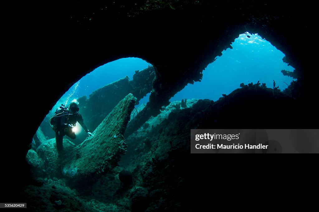 A diver explores a bronze propeller and collapsed stern section in the shallows of the stern section of the wreck of the 1867 wreck of the RMS Rhone.