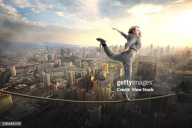 woman walking tightrope over city - woman tightrope stock pictures, royalty-free photos & images